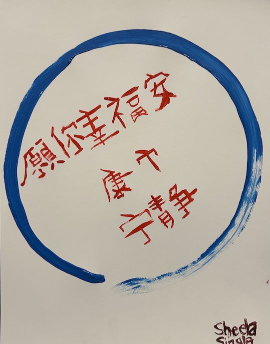Enso with May you be happy and peaceful written inside in mandarin. The enso is blue and the writing is red.